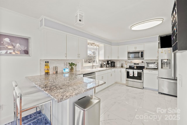 kitchen with kitchen peninsula, appliances with stainless steel finishes, decorative backsplash, and white cabinetry