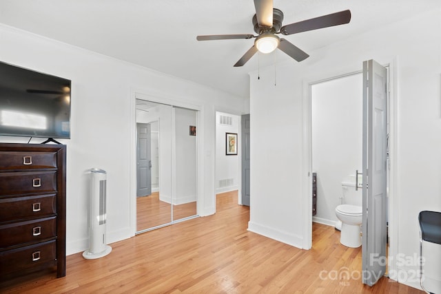 bedroom with a closet, connected bathroom, light hardwood / wood-style floors, and ceiling fan