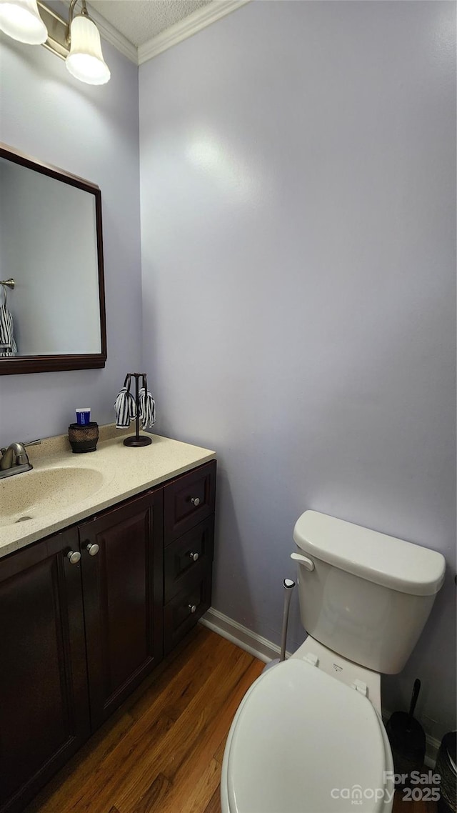 bathroom featuring crown molding, hardwood / wood-style floors, vanity, and toilet