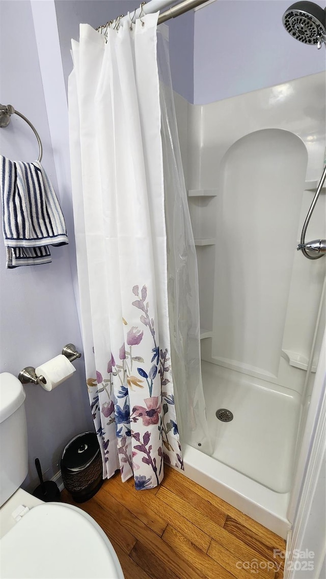 bathroom with hardwood / wood-style flooring, toilet, and walk in shower