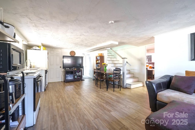 living room with a textured ceiling and light hardwood / wood-style flooring