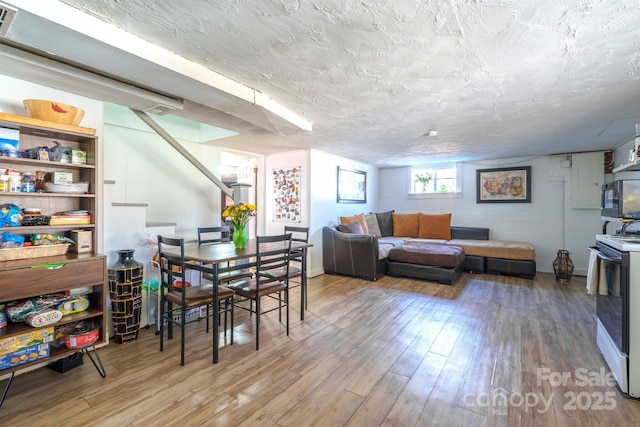 dining room featuring wood-type flooring and a textured ceiling