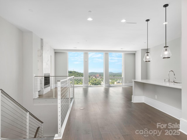 unfurnished living room with floor to ceiling windows, sink, and dark hardwood / wood-style flooring