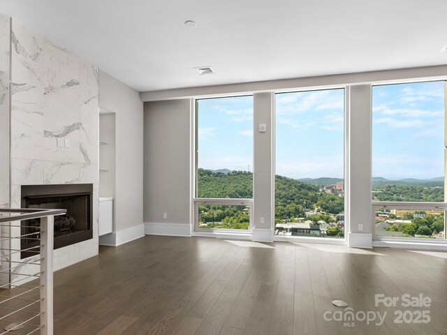 unfurnished living room with a premium fireplace, dark wood-type flooring, and a mountain view