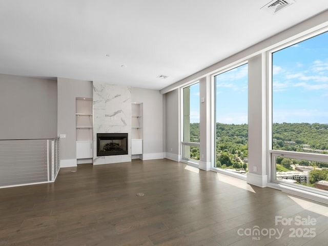 unfurnished living room with a fireplace, dark hardwood / wood-style floors, and built in features