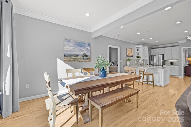 dining room featuring beamed ceiling, light hardwood / wood-style floors, ornamental molding, and sink