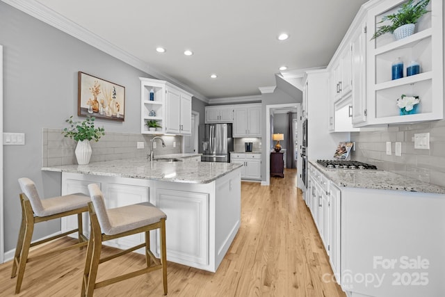 kitchen featuring stainless steel appliances, tasteful backsplash, light stone counters, kitchen peninsula, and white cabinets