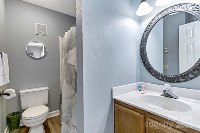 bathroom with hardwood / wood-style floors, vanity, toilet, and a textured ceiling