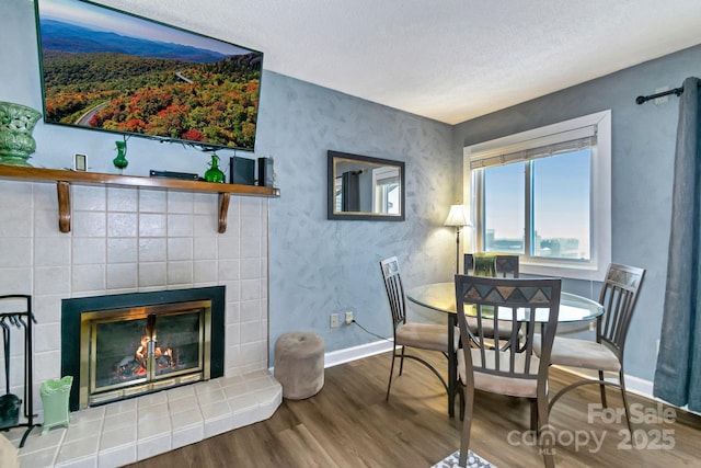 dining area with hardwood / wood-style floors and a tiled fireplace