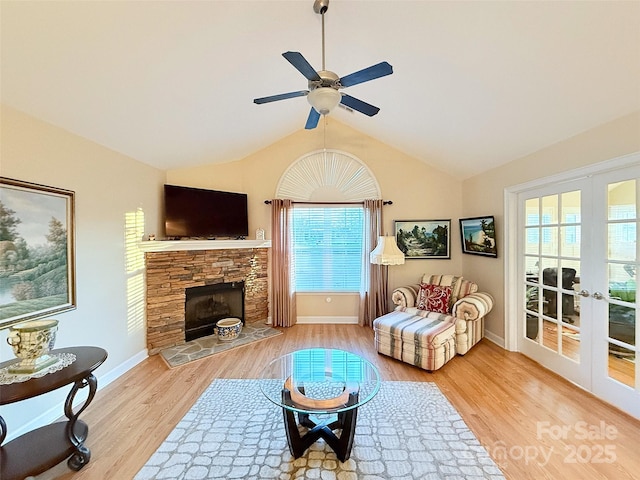 living room featuring french doors, ceiling fan, light hardwood / wood-style floors, and a stone fireplace