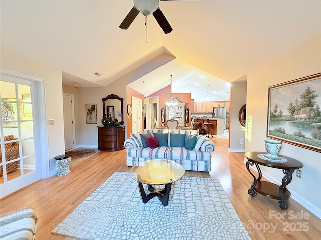 living room featuring light wood-type flooring, vaulted ceiling, and ceiling fan with notable chandelier