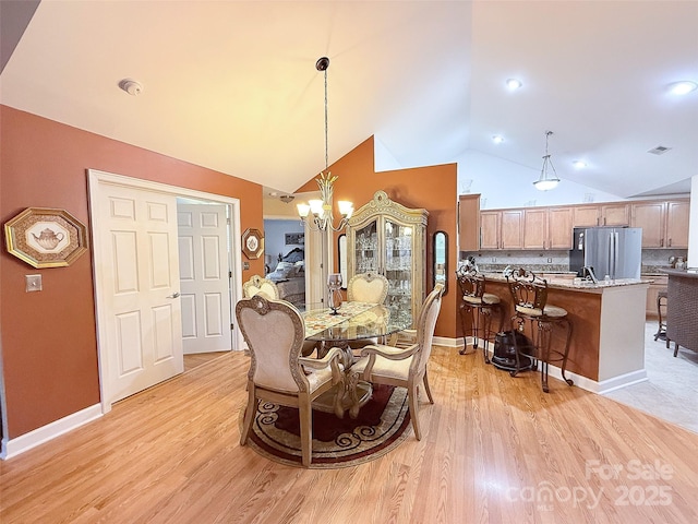 dining space with vaulted ceiling, an inviting chandelier, and light hardwood / wood-style floors