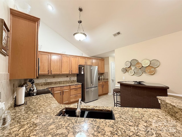 kitchen featuring decorative light fixtures, stainless steel fridge, high vaulted ceiling, backsplash, and sink