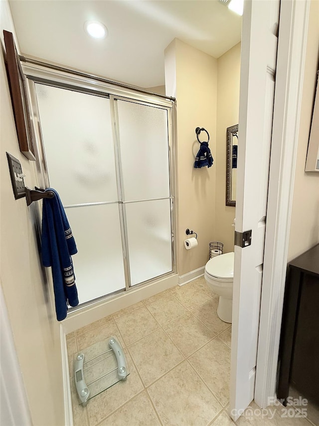 bathroom featuring toilet, tile patterned flooring, and a shower with shower door