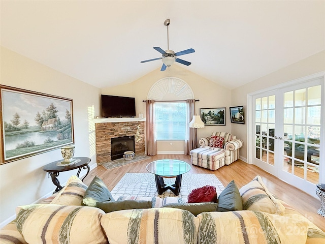 living room with ceiling fan, french doors, light wood-type flooring, and a stone fireplace