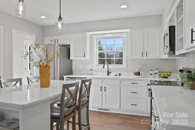 kitchen with white cabinets, stainless steel appliances, a breakfast bar area, and sink