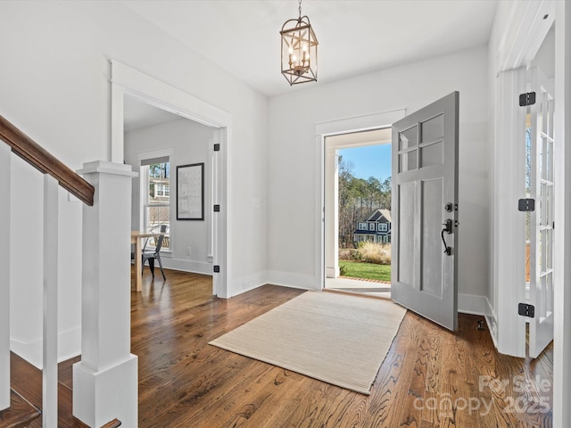 entryway featuring dark wood-type flooring and an inviting chandelier