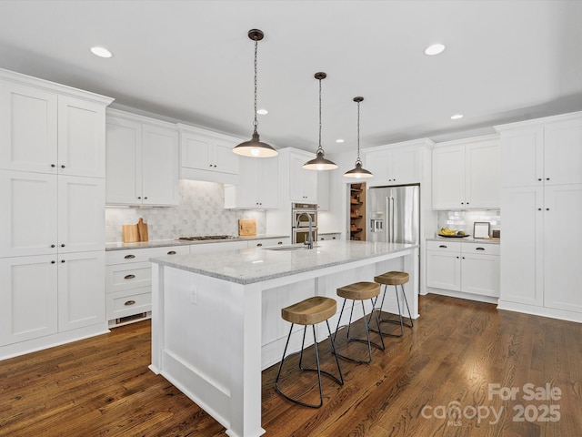 kitchen featuring stainless steel appliances, a kitchen island with sink, dark wood-type flooring, decorative light fixtures, and white cabinetry