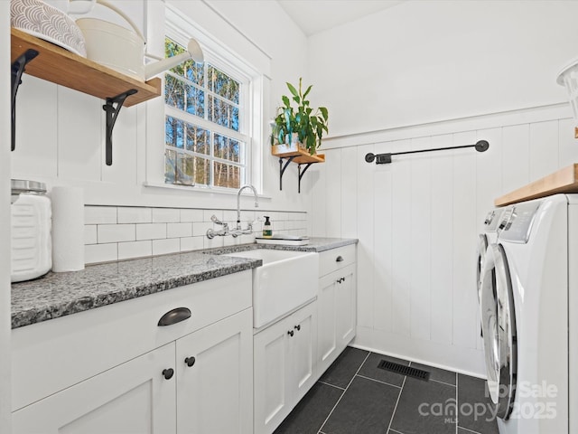 clothes washing area featuring dark tile patterned floors, cabinets, separate washer and dryer, and sink