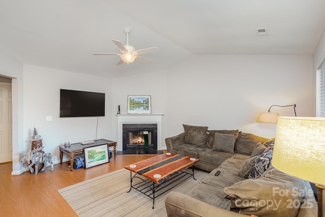 living room featuring ceiling fan, lofted ceiling, a fireplace, and hardwood / wood-style floors