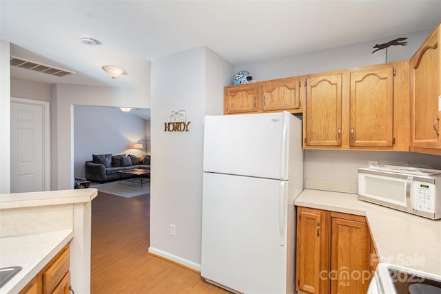 kitchen with white appliances and light hardwood / wood-style floors