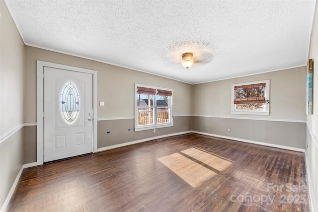 foyer entrance featuring a textured ceiling, crown molding, and dark wood-type flooring