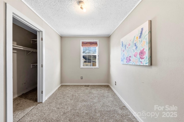 unfurnished bedroom with a textured ceiling, light colored carpet, a spacious closet, and a closet