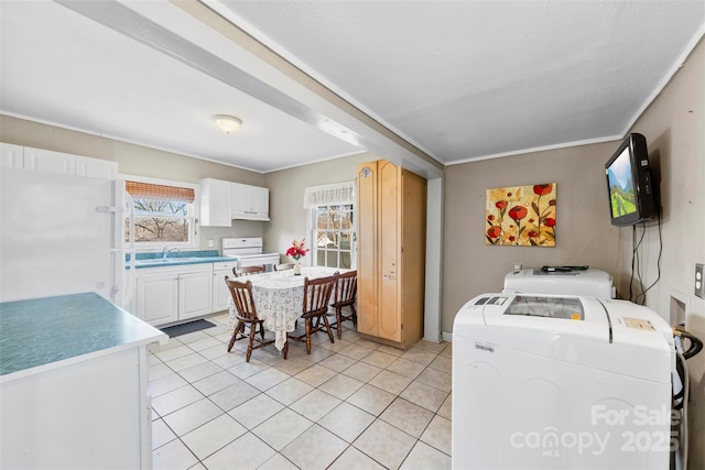 interior space featuring white cabinets, washing machine and dryer, white appliances, and a wealth of natural light