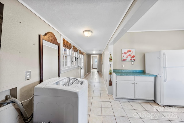 kitchen with washing machine and clothes dryer, light tile patterned flooring, white fridge, a textured ceiling, and white cabinets