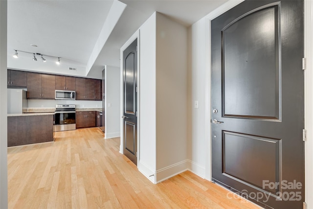 kitchen featuring dark brown cabinetry, light hardwood / wood-style flooring, rail lighting, and appliances with stainless steel finishes