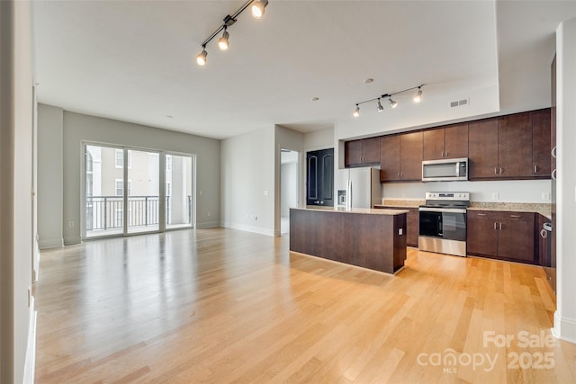 kitchen featuring dark brown cabinetry, stainless steel appliances, a kitchen island with sink, and light wood-type flooring