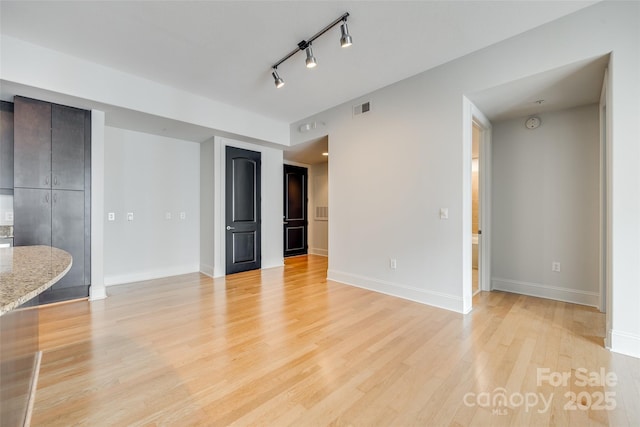 unfurnished living room featuring track lighting and light hardwood / wood-style floors