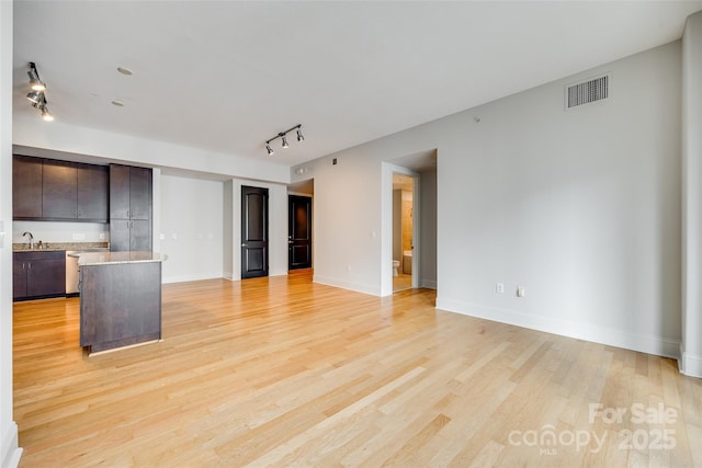 unfurnished living room with rail lighting, sink, and light hardwood / wood-style flooring