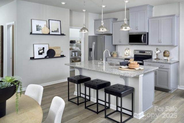 kitchen with gray cabinets, appliances with stainless steel finishes, and tasteful backsplash