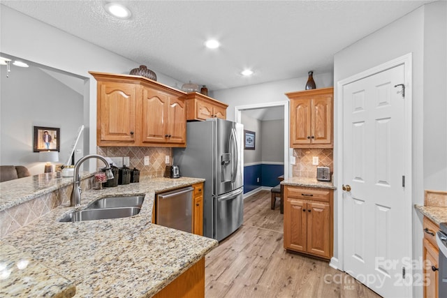 kitchen with light stone counters, stainless steel appliances, sink, and decorative backsplash