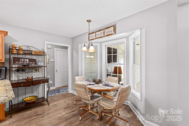 dining room featuring a notable chandelier, light hardwood / wood-style floors, and a textured ceiling