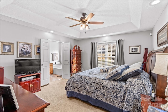 carpeted bedroom featuring a raised ceiling, connected bathroom, a textured ceiling, and ceiling fan