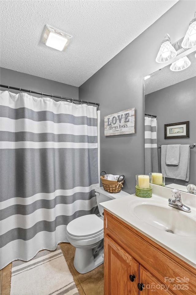 bathroom featuring vanity, tile patterned floors, a textured ceiling, and toilet