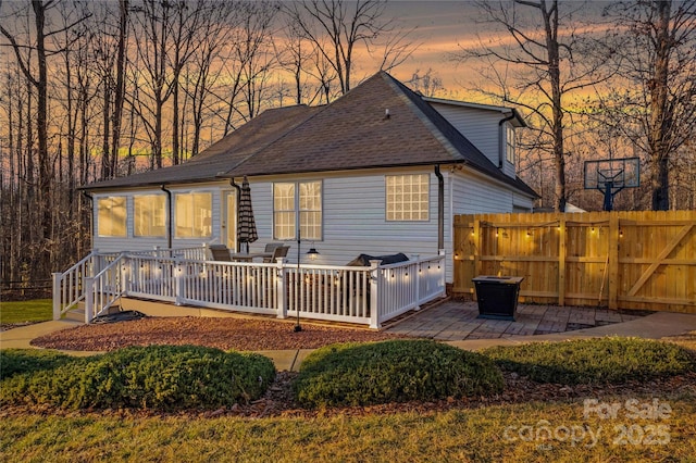 back house at dusk with a deck and a patio area