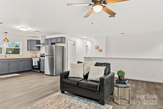 living room with ceiling fan, light hardwood / wood-style flooring, and sink