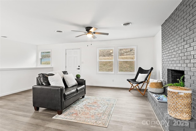 living room with ceiling fan, a fireplace, and hardwood / wood-style flooring