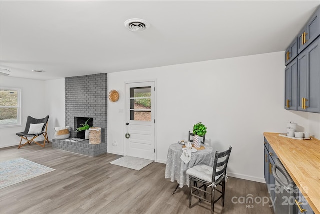 dining area with a fireplace, light hardwood / wood-style flooring, and a healthy amount of sunlight