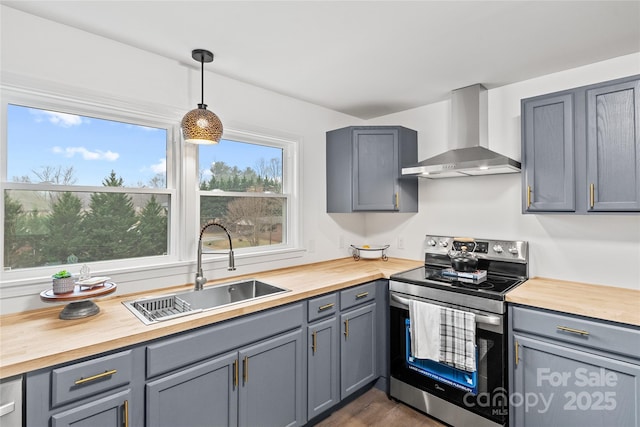 kitchen with wall chimney exhaust hood, sink, decorative light fixtures, gray cabinets, and stainless steel electric range oven