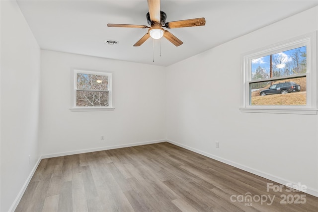 empty room featuring ceiling fan, a healthy amount of sunlight, and light hardwood / wood-style flooring