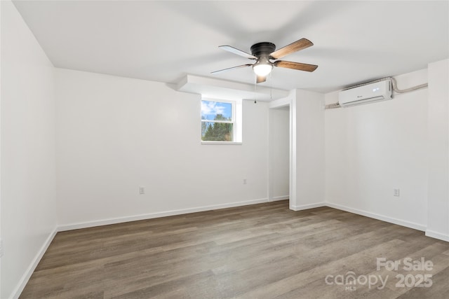 spare room with wood-type flooring, a wall mounted AC, and ceiling fan