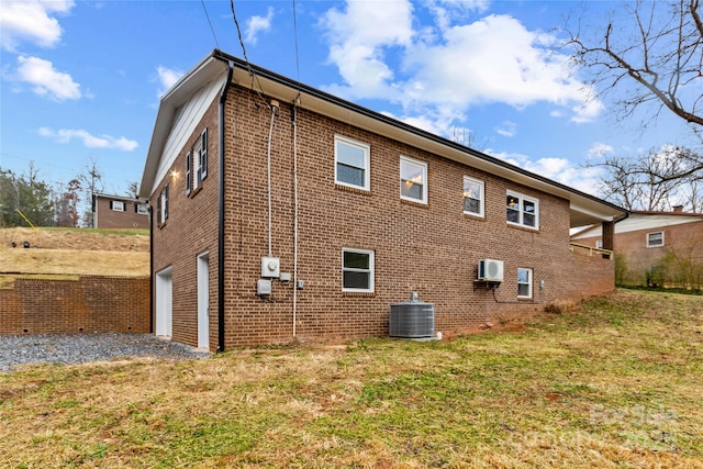 view of side of home with a lawn, a wall mounted air conditioner, central AC unit, and a garage