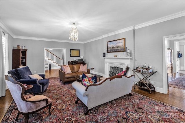 living room with crown molding, a fireplace, a chandelier, and wood-type flooring