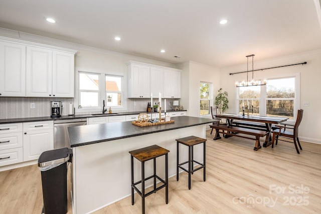 kitchen featuring white cabinetry, tasteful backsplash, decorative light fixtures, a center island, and dishwasher