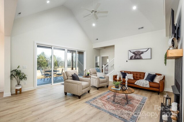 living room with high vaulted ceiling, ceiling fan, and light wood-type flooring