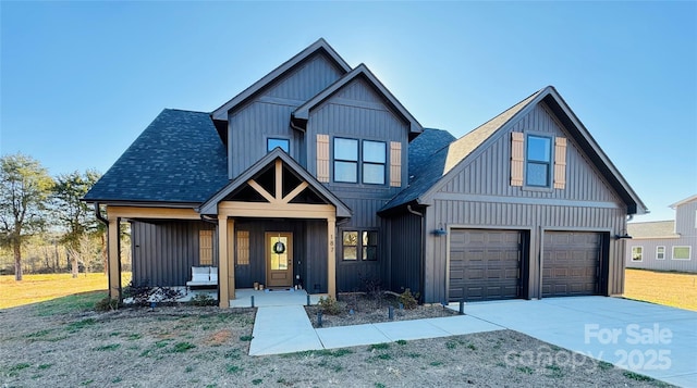 view of front of property featuring driveway, a shingled roof, covered porch, board and batten siding, and a front yard